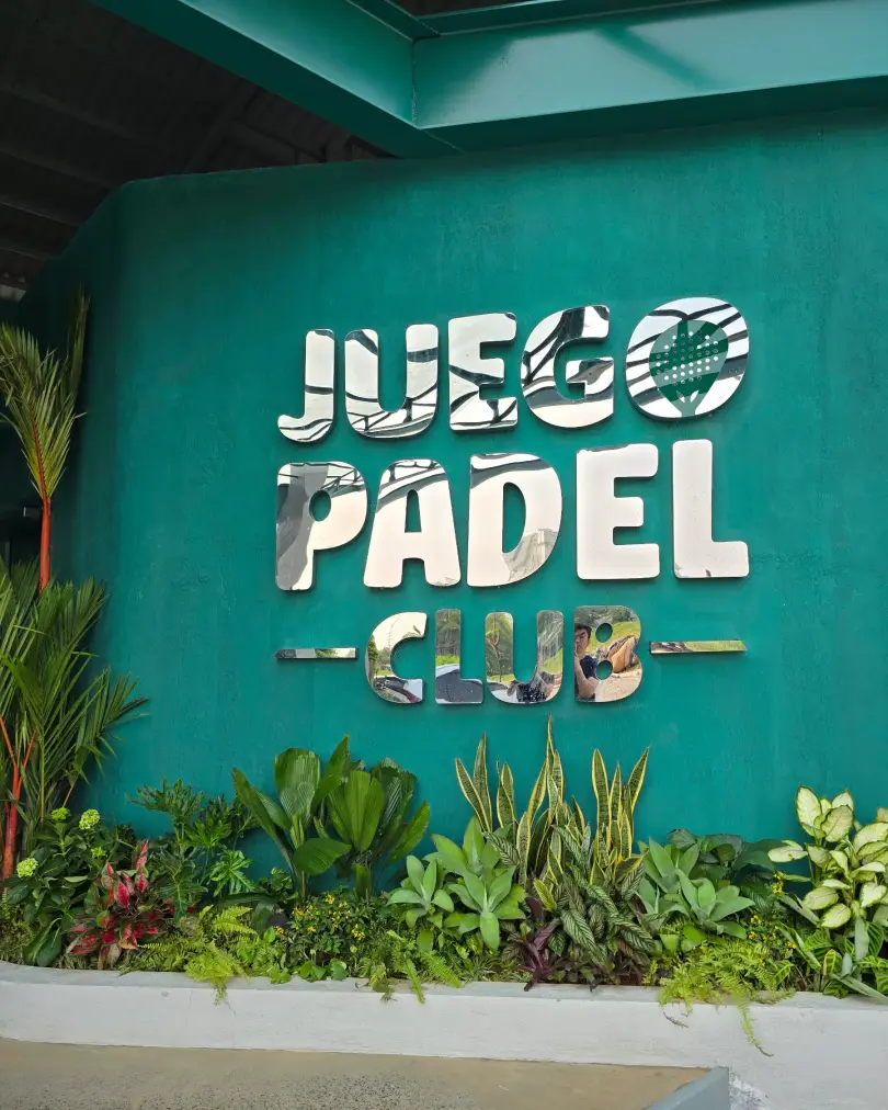 Juego Padel Club logo on a green wall